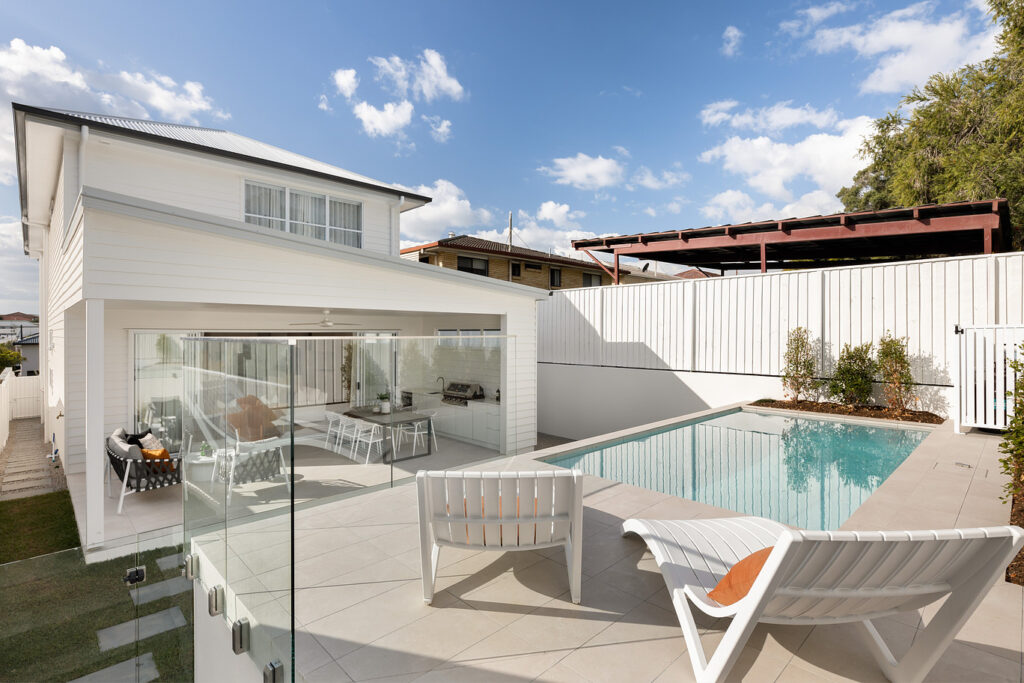 A sleek frameless glass pool fence providing an unobstructed safety barrier for a modern tiled pool area and outdoor entertaining patio.